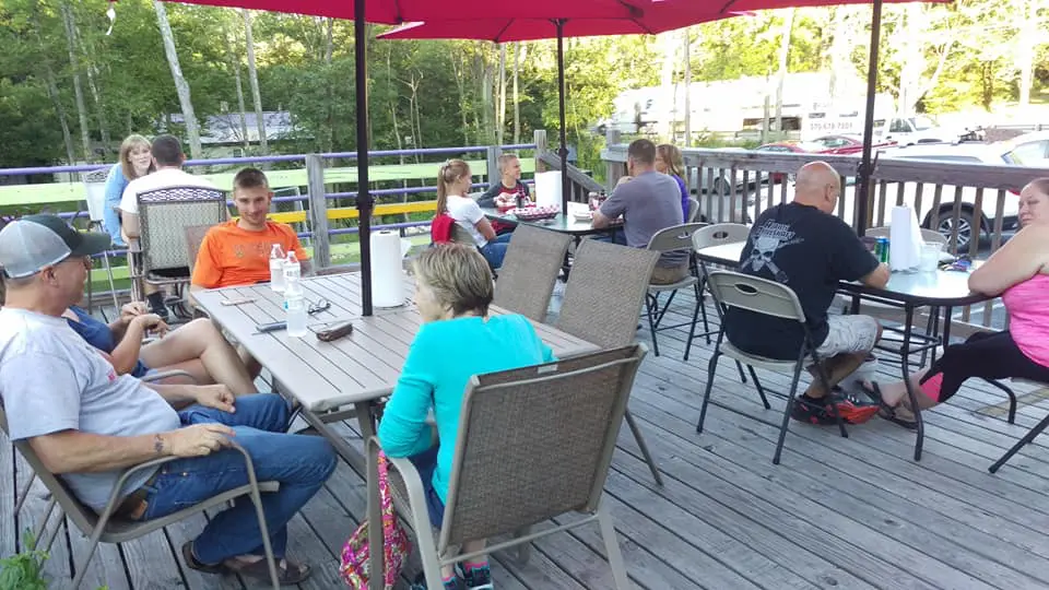 A group of people sitting at tables under an umbrella.