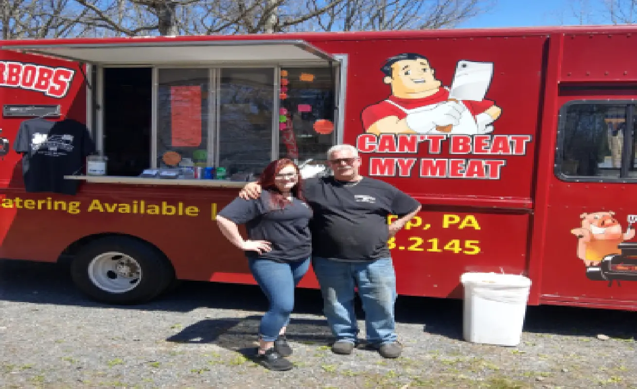 A man and woman standing in front of a food truck.