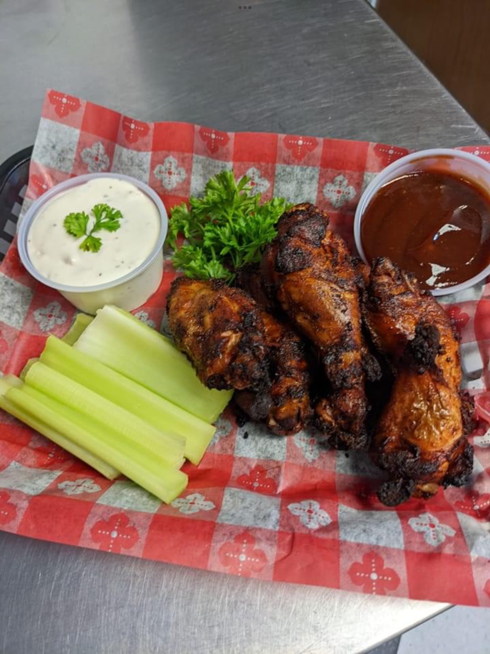A basket of chicken wings with celery and ranch.