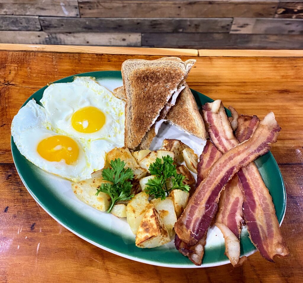 A plate of food with bacon, eggs and toast.